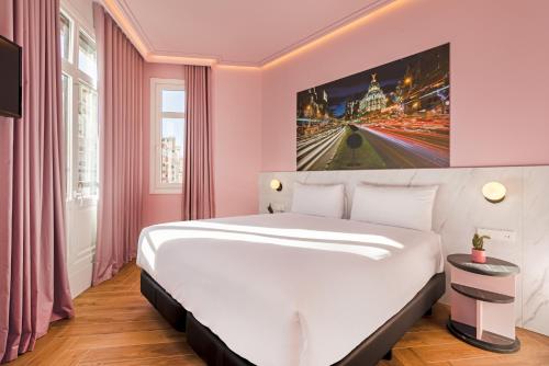 a large white bed in a room with pink walls at Ikonik Gran Vía in Madrid