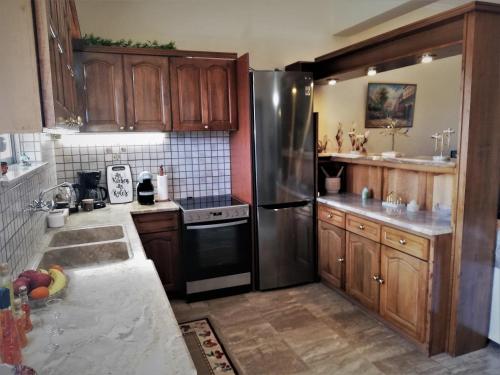 eine Küche mit Holzschränken und einem Kühlschrank aus Edelstahl in der Unterkunft sapfo's house in Ágios Ioánnis