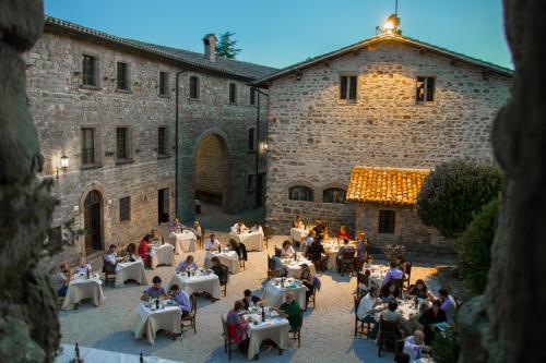 a group of people sitting at tables in the courtyard of a building at Castello Di Petroia Dimora d'Epoca in Gubbio