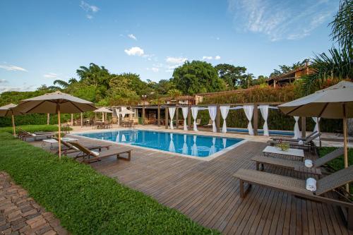 a swimming pool with benches and umbrellas in a yard at Pousada Brisa da Serra in Tiradentes