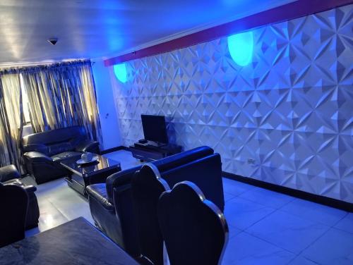 um quarto com cadeiras e uma televisão e uma parede com luzes azuis em Golden tulips festival mall em Lagos
