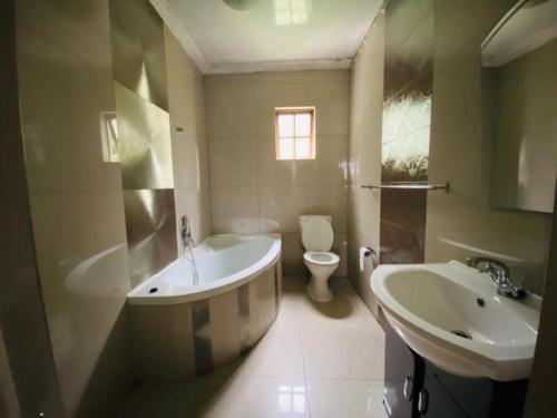 ein Badezimmer mit einer Badewanne, einem WC und einem Waschbecken in der Unterkunft Bogotá in Pietermaritzburg