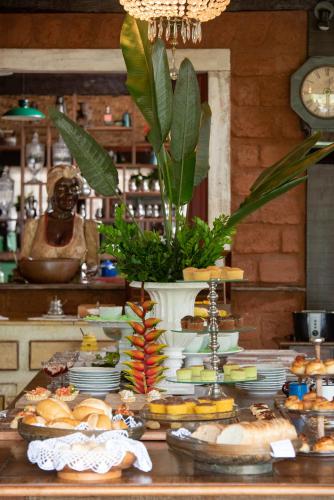 a table with plates of food and a vase of food at Brisa da Serra Pousada Boutique in Tiradentes