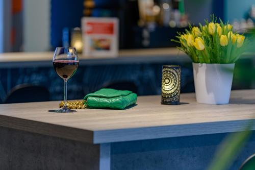 a glass of wine sitting on a table with flowers at ibis Köln Frechen in Cologne