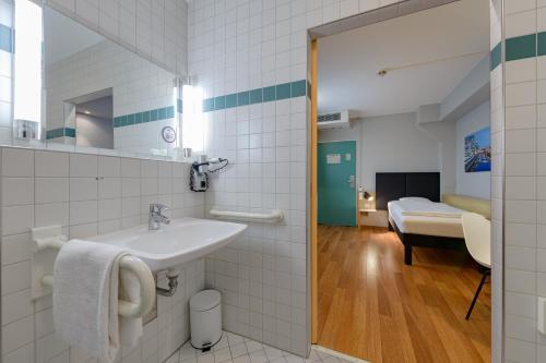 baño con lavabo y habitación con cama en ibis Köln Frechen, en Colonia