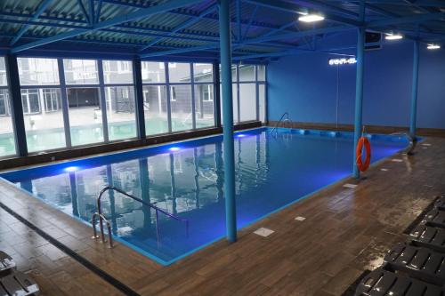 an indoor swimming pool with blue paint and wood floors at Готель Гармонія. Термально-оздоровчий комплекс. in Mynay