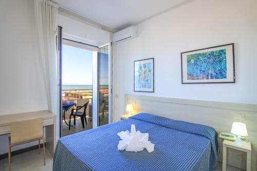 a bedroom with a blue bed with a white flower on it at Hotel Duca di Kent in Cesenatico