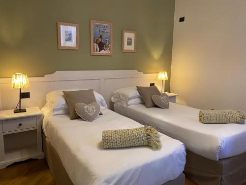 due letti in una camera d'albergo con lenzuola bianche di Il Molo Di Hotel Villa Aurora a Lezzeno