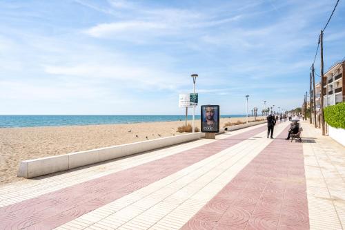 a person walking down a sidewalk on the beach at Kaixo in Calafell