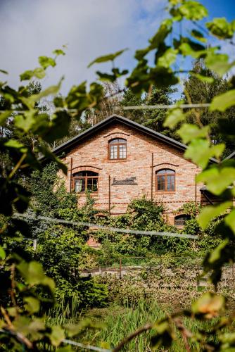 a brick house is seen through the trees at Tabun in Gdańsk