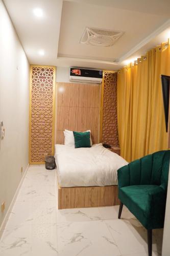 a bedroom with a bed and a green chair at NuvaHotel in Islamabad