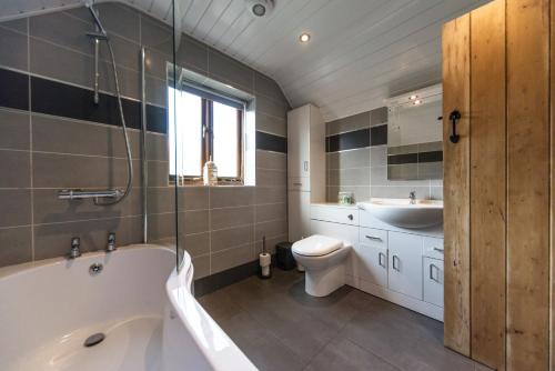 a bathroom with a tub and a toilet and a sink at Dale End Cottage, Brassington in Brassington