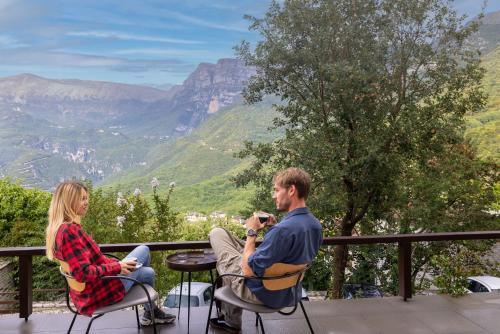 a man and woman sitting at a table with a view of mountains at Aristi Mountain Resort in Aristi