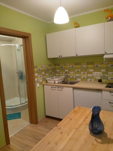 cocina con paredes verdes, armarios blancos y mesa en Apartamenti pie jūras Latvijā, en Plieņciems