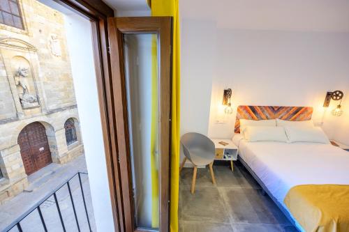 een slaapkamer met een bed, een stoel en een raam bij Hospedería La casa del Alarife in Úbeda