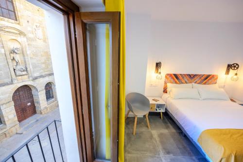 a bedroom with a bed and a chair and a window at Hospedería El Alarife in Úbeda
