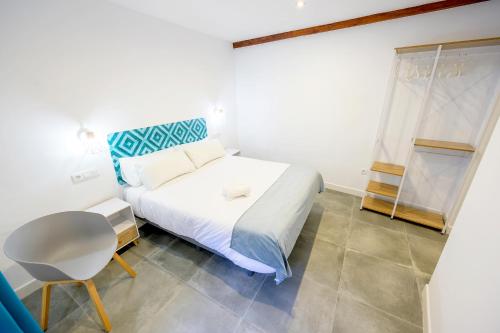 a bedroom with a white bed and a chair at Hospedería El Alarife in Úbeda