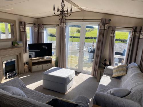 een woonkamer met twee banken en een tv en een televisie bij Luxury Lake District Holiday Home-Sleeps 4 in Cockermouth