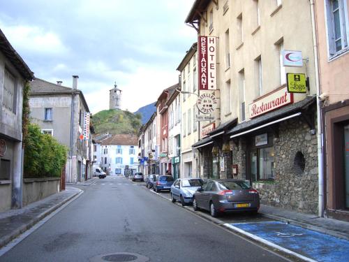 an empty city street with cars parked on the street at Logis Hôtel Restaurant de la Poste in Tarascon-sur-Ariège