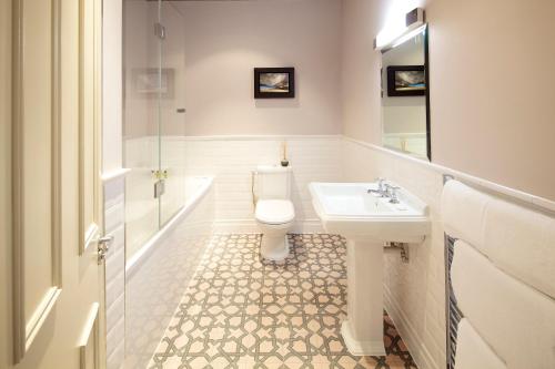 a white bathroom with a toilet and a sink at 8 Beresford Street in Saint Helier Jersey