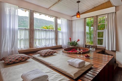 Habitación con 2 camas y mesa con ventanas. en Brisa da Serra Pousada Boutique, en Tiradentes