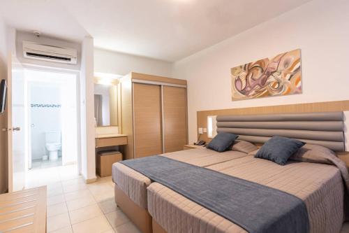 a bedroom with a large bed and a bathroom at Vrissaki Hotel Apartments in Protaras