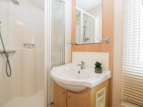 uma casa de banho com um lavatório branco e um chuveiro em The Hideaway em Weymouth