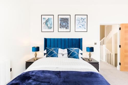 伯明罕的住宿－Sydenham Place - Birmingham City Centre Jewellery Quarter - A Trio of Premium High End Town/Penthouses - 4 Bedrooms & Secure EV Parking，一间卧室配有一张带两盏灯的蓝色和白色的床。