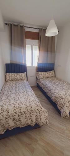 een slaapkamer met 2 bedden en een raam bij El Refugio in Tetouan