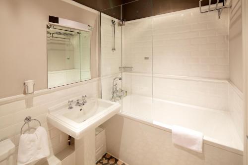 a white bathroom with a sink and a shower at 8 Beresford Street in Saint Helier Jersey