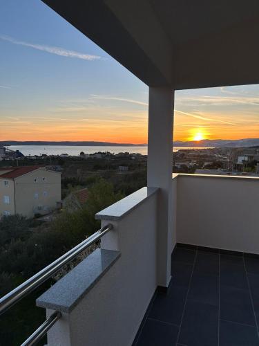 uma vista para o pôr-do-sol a partir da varanda de uma casa em Apartment Marko with a beautiful view of the sea em Kaštel Sućurac