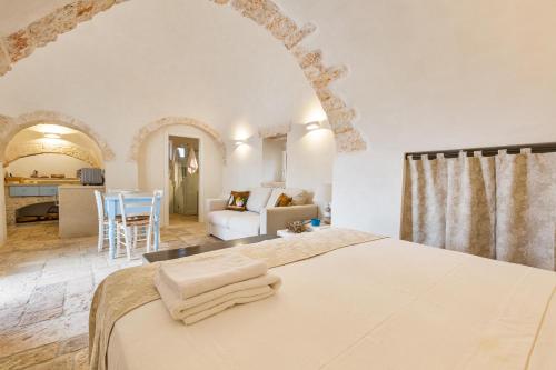 Masseria Macchia في سيغلي ميسابيكا: غرفة نوم مع سرير وغرفة معيشة