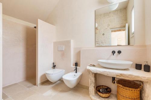 uma casa de banho branca com um lavatório e um WC em Masseria Macchia em Ceglie Messapica