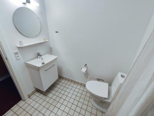 a bathroom with a toilet and a sink and a mirror at Rønnes Hotel in Fjerritslev