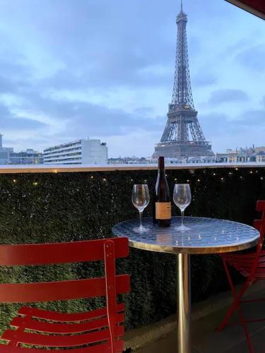 - une table avec deux verres à vin et la tour de l'eiffel dans l'établissement Le Suffren-Eiffel Appartement, à Paris