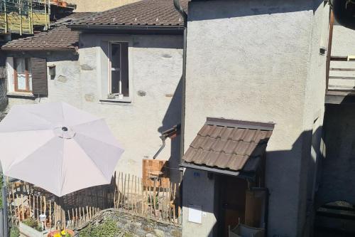 un paraguas blanco delante de una casa en Spacious house in village center with a view, en Ronco sopra Ascona
