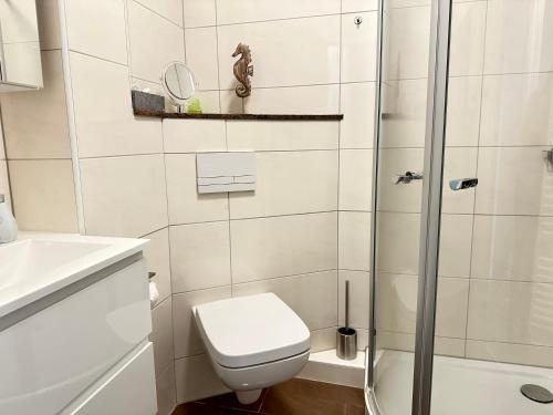 a white bathroom with a toilet and a shower at Vogelnest in Grömitz