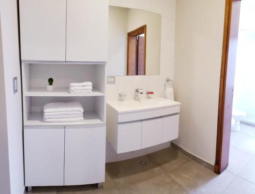 W białej łazience znajduje się umywalka i lustro. w obiekcie Altos Catamarca w mieście San Fernando del Valle de Catamarca