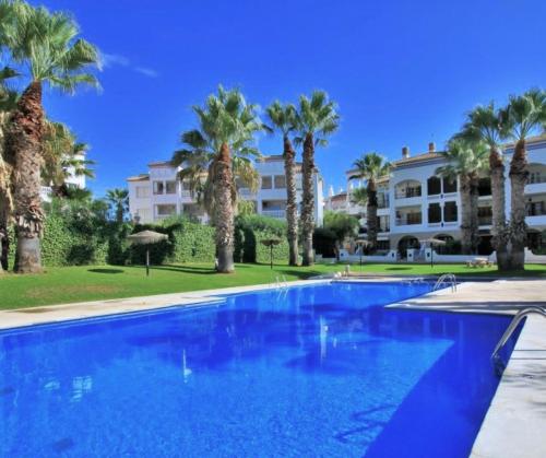 a large swimming pool with palm trees and a building at Villamartin Plaza No 154 in Orihuela