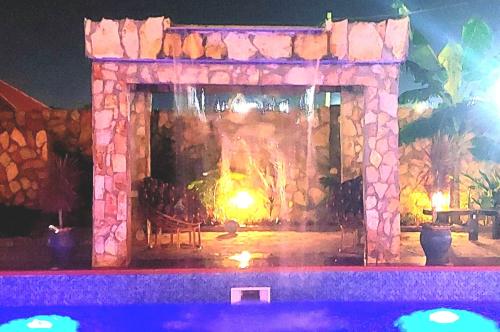 a stone fireplace with a table in front of it at night at Blue Palm Resort Ghana in Abia