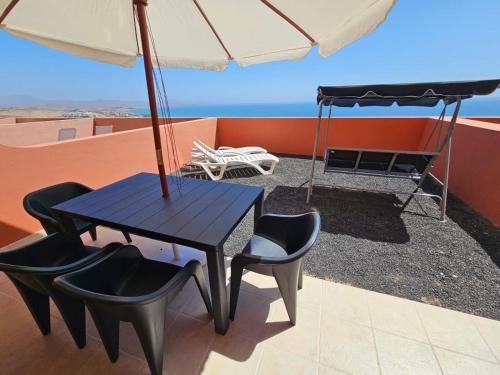 einen Tisch und Stühle mit Sonnenschirm auf dem Dach in der Unterkunft Your Ocean Blue in Costa Calma