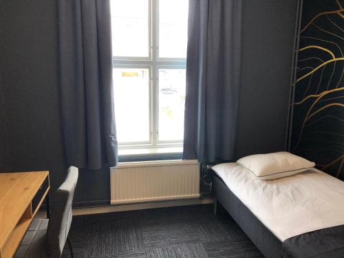 Mini-Hotel Borås Regementet في بوراس: غرفة نوم صغيرة بها سرير ونافذة