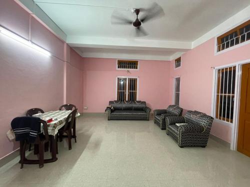 a living room with pink walls and a table and chairs at MriMan Homestay in Jorhāt