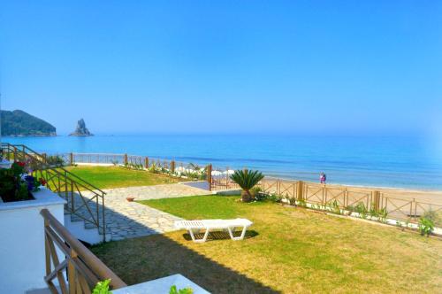 a white bench sitting on the grass near the beach at Beachfront 4-bed luxury suite - Agios Gordios, Corfu, Greece in Agios Gordios