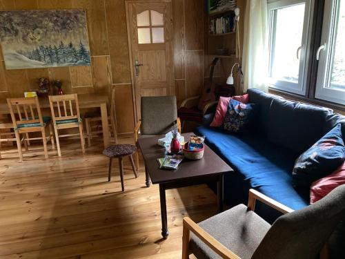 a living room with a blue couch and a table at Cozy mountain cottage with terrace in Dolni Lomna in Dolní Lomná