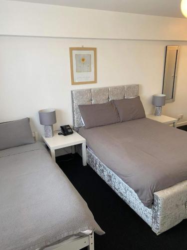 a bedroom with two beds and two tables with lamps at Green Acre Motel in North Cornelly