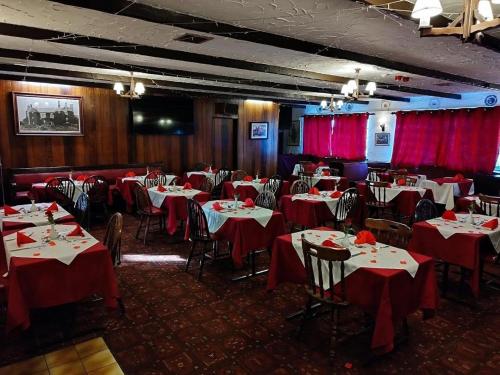 a dining room with red clothed tables and chairs at Green Acre Motel in North Cornelly