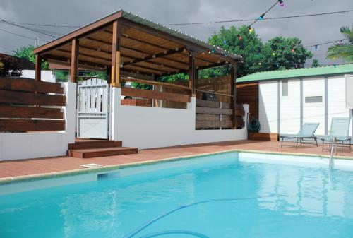 a swimming pool with a pavilion next to a house at Les bungalows du chateau d'Ô in Petite Île
