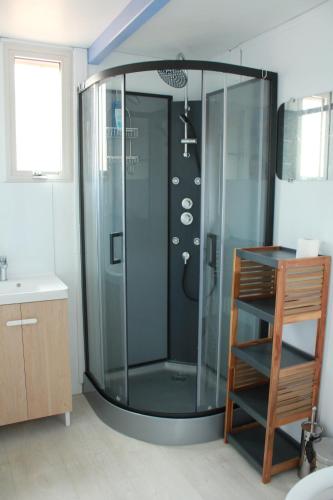 a shower with a glass door in a bathroom at Les bungalows du chateau d'Ô in Petite Île
