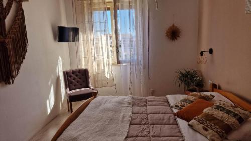 a bedroom with a bed and a chair and a window at BOHO ROOMS MARTA in Priolo Gargallo